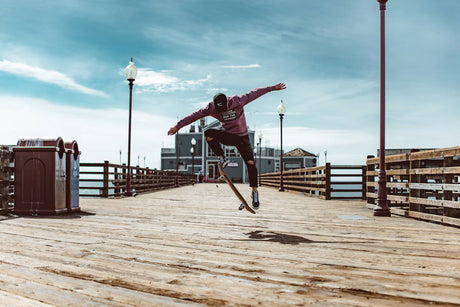 Skateur en plein ollie sur un ponton en bois, la planche décolle sous ses pieds