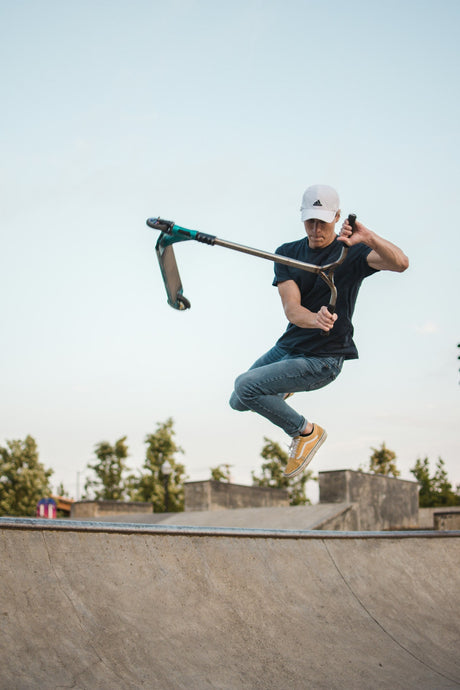 Rider en trottinette freestyle faisant un tailwhip au-dessus d'une rampe de skatepark