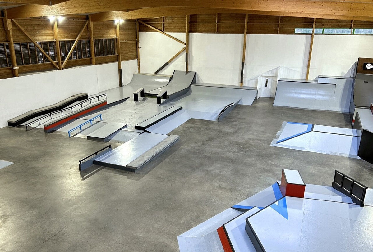 Intérieur de la Halle de skate Cœur d'Essonne à Villiers-sur-Orge : modules street, ledges, rails et quarters sous charpente bois