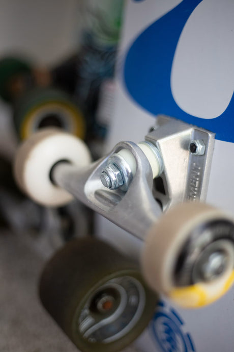 Gros plan sur un truck de skateboard en aluminium avec ses gommes, son écrou de kingpin et ses roues, devant d'autres skates