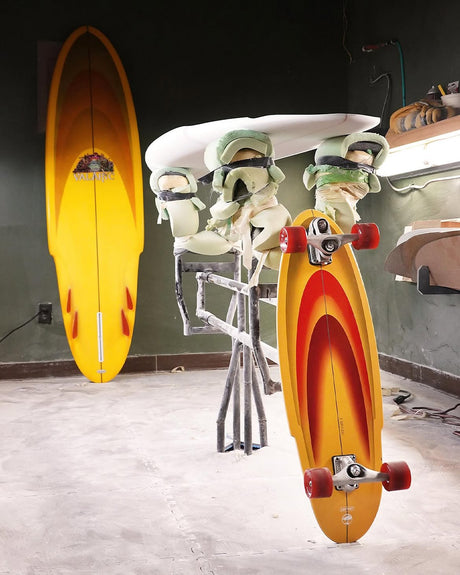 Surfskate Arbor Carver C7 Jordan Brazie 33" dans l'atelier de shape, à côté de la planche de surf Valaric qui a inspiré son design